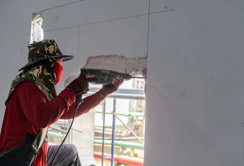 Worker using electric drill hammer to cut the wall concrete brick. Stock Photos