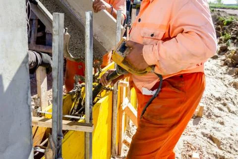Worker is using electric vibratory to compact concrete in wooden mold Stock Photos