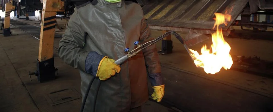 Worker using a flame torch in an industrial workshop during daytime hours t.. Stock-Fotos