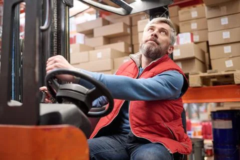Worker using forklift to load cargo on shelves Stock Photos