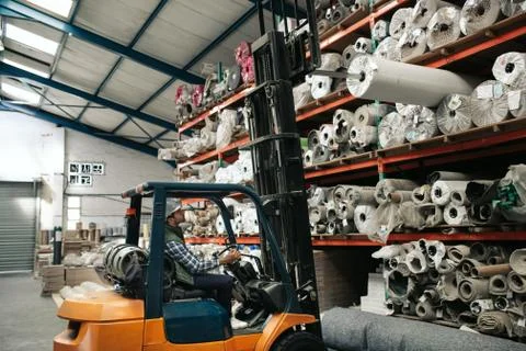 Worker using a forklift to remove stock from warehouse shelves Stock Photos