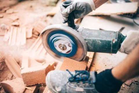Worker using grinder on construction site for cutting bricks, debris Stock Photos
