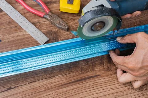 Worker using grinding machine to cut steel roof batten. Stock Photos