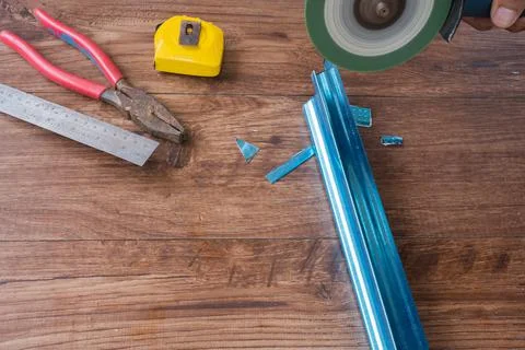 Worker using grinding machine to cut steel roof batten. Foto stock