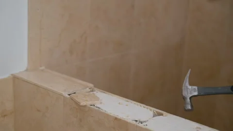 Worker using a hammer to remove ceramic tiles from a bathroom wall during Stock Footage 332185745