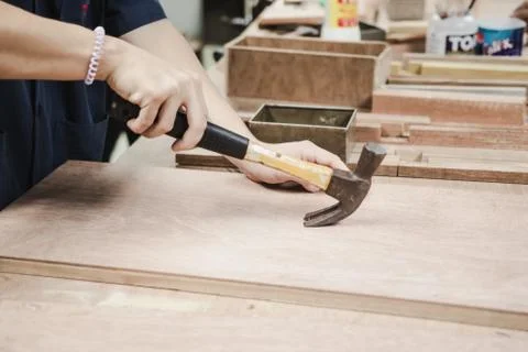 Worker using hammer to remove nail from piece of wood. Stock Photos