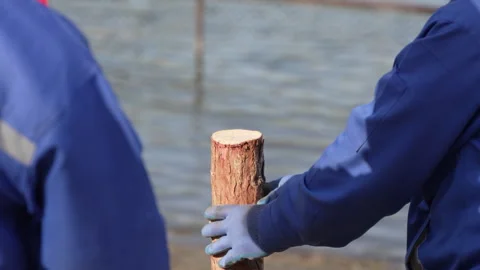 Worker using a hammer to smash a wooden pile to install a wooden pile Stock Footage 240201167