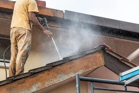 Worker using high pressure water jet spray gun to wash and clean dirt from Stock Photos