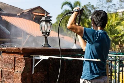 Worker using high pressure water jet spray gun to wash and clean away dirty wall Stock Photos