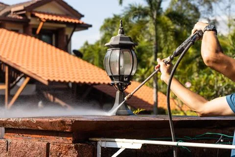 Worker using high pressure water jet spray gun to wash and clean away dirty wall Foto stock
