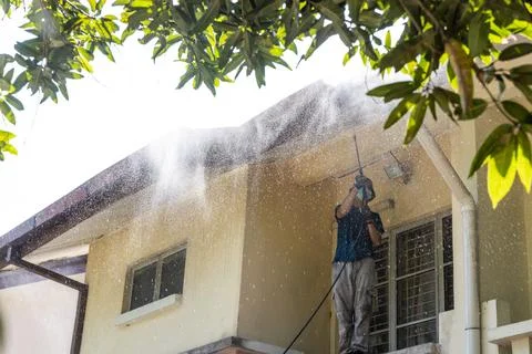 Worker using high pressure water jet spray gun to wash and clean dirt from .. Stock Photos