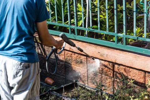 Worker using high pressure water jet spray gun to wash and clean away dirty.. Stock Photos