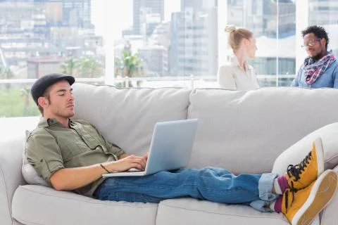 Worker using his laptop while laying on a couch Fotos Stock