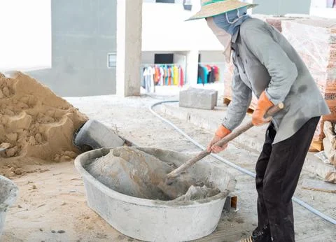 Worker using hoe to mixing sand and cement manually. Foto stock