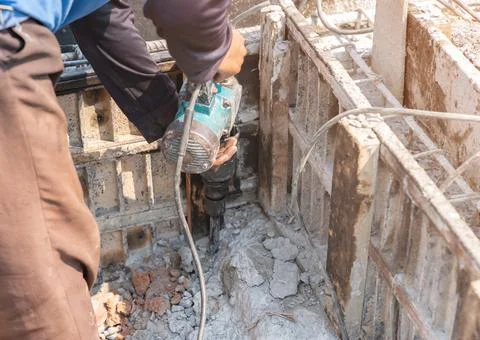 Worker using a jackhammer to drill floor for pull out beam framework. Stock Photos
