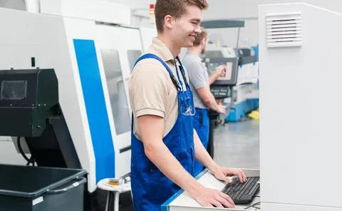 Worker using keyboard to enter data into a machine on factory floor Stock Photos