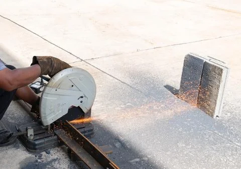 Worker using a metal chop saw to cut steel square tubing with bright sparks.. Stockfoto's