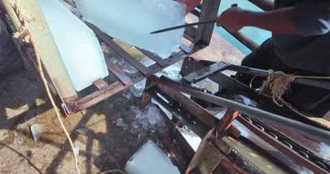  worker using a metal hook to guide a large block of ice into a crusher Stock Footage 327440436