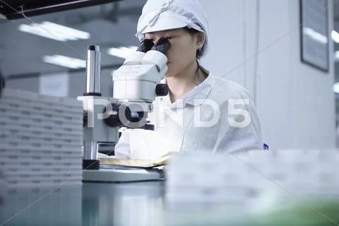 Worker Using Microscope In Factory That Specialises In Creating Functional