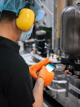 Worker using the mobile while standing in a brewery Stock Photos