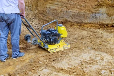 Worker using a plate compactor on a construction site to prepare the ground for 스톡 사진