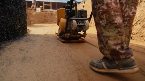 Worker using a plate compactor for soil compaction Stock Photos