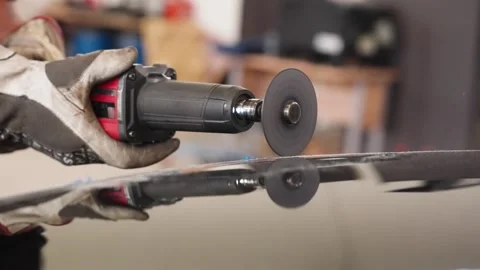 Worker using pneumatic angle grinder on reflective vehicle panel during Stock Footage 336672245