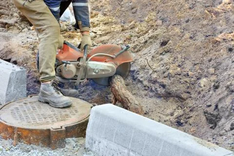 A worker using a portable gasoline saw clears the site and cuts the powerful  Stock Photos