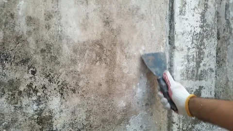 Worker using a putty knife to scrape peeling paint from a damaged wall. Stock Footage 341900330