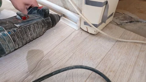 Worker using rotary hammer drill for baseboard installation Stock Footage 326150381