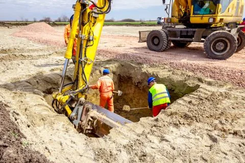 Worker is using shovel to set up right measures in square trench Stock Photos