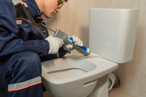 Worker using silicone or sealant to install the toilet bowl Stock Photos