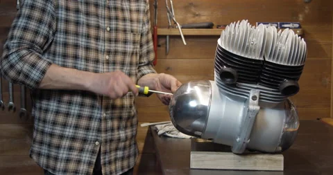 Worker using skrewdriver to assemble motorcycle engine after repair in garage 動画素材 147726720
