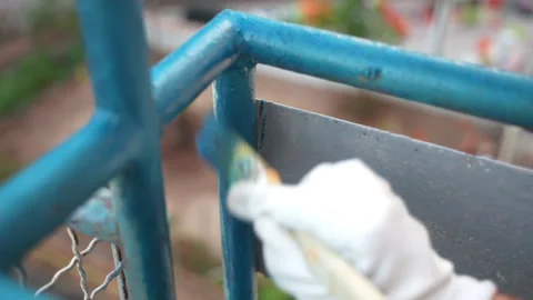 Worker using soft paintbrush for painting balcony iron frames with blue colour Stockbeeldmateriaal 226149412