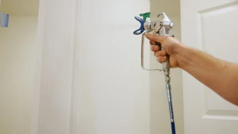 Worker using a spray gun to paint an interior door during renovation. Video stock 332185937