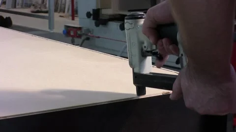 Worker using staple gun to fix back side of the closet in furniture factory. Stockbeeldmateriaal 57216764