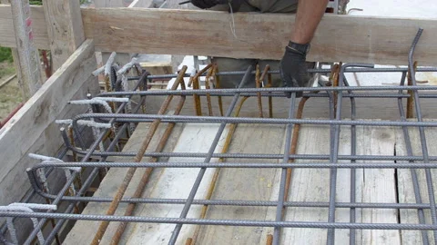 Worker using steel wire and pincers to secure rebar before concrete is poured Video stock 143281202