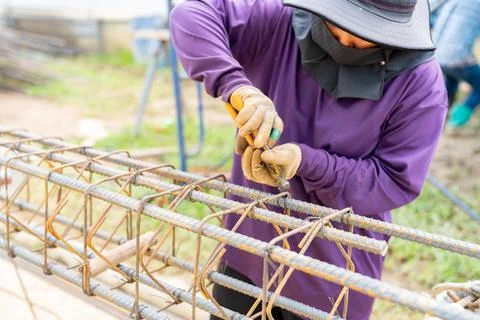 Worker using steel wire for securing steel bars with wire rod for reinforceme Foto stock