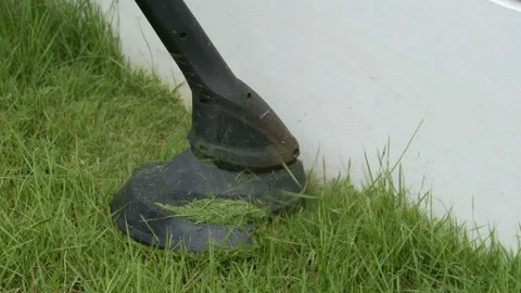 Worker using a string lawn trimmer mower cutting grass at home Stock Footage 155886643