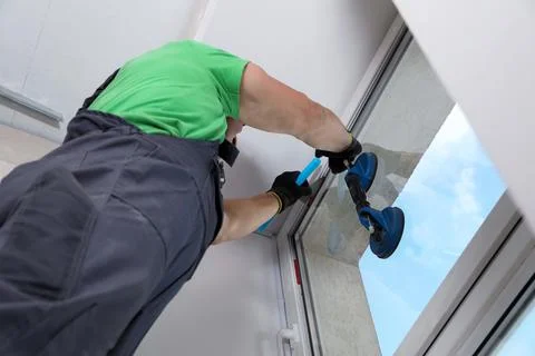 Worker using suction lifter for window installation indoors, low angle view Stock Photos