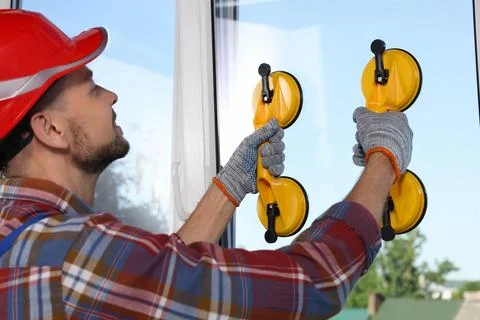 Worker using suction lifters during plastic window installation indoors Stock Photos