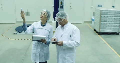 Worker using tablet and talking to colleague in modern warehouse. Storage Stock Footage 101099162