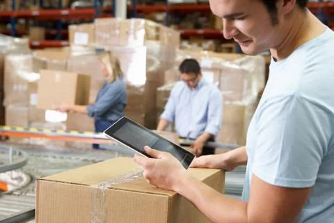 Worker Using Tablet Computer In Distribution Warehouse Stock Photos