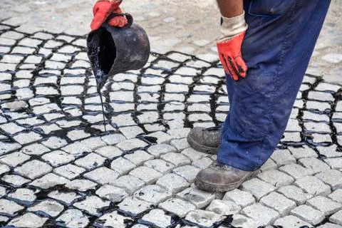 Worker using tar bucket and pouring bitumen into the joints 2 Stock Photos