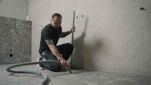 Worker using a tool to prepare a surface for tile installation Video stock 317380680