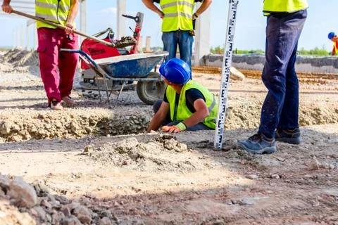 Worker is using tool to set up right measures in square trench Stock Photos