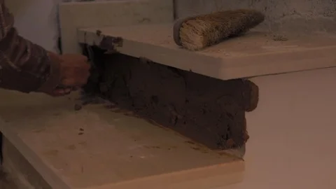 Worker using a trowel to apply brown cement mixture, made with sand, gravel and Stock Footage 110771463