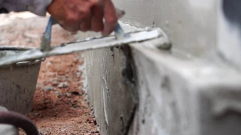 Worker using trowel to finish wet concrete wall at construction site  Stock Footage 112946292