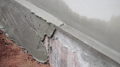 Worker using trowel to finish wet concrete wall at construction site  Stock Footage 112946346