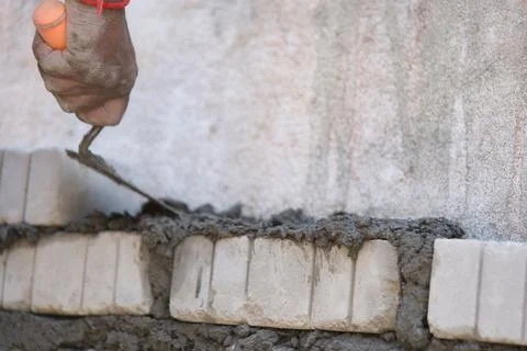Worker using trowel to put cement mortar on the wall Stock Photos